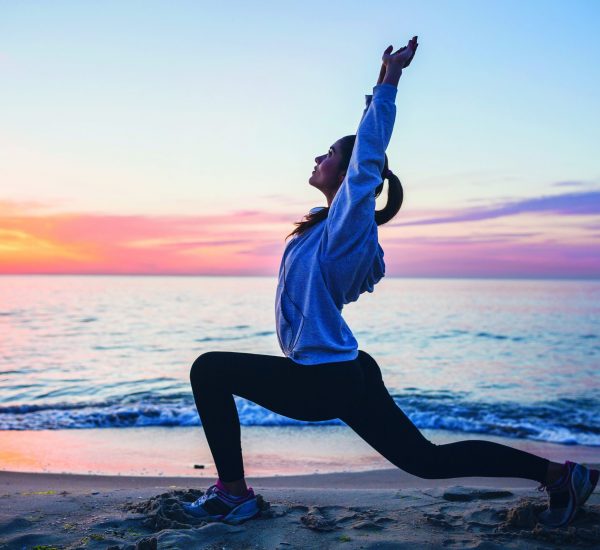 young woman doing sport exercises on sunrise beach in morning, stretching, healthy lifestyle, yoga